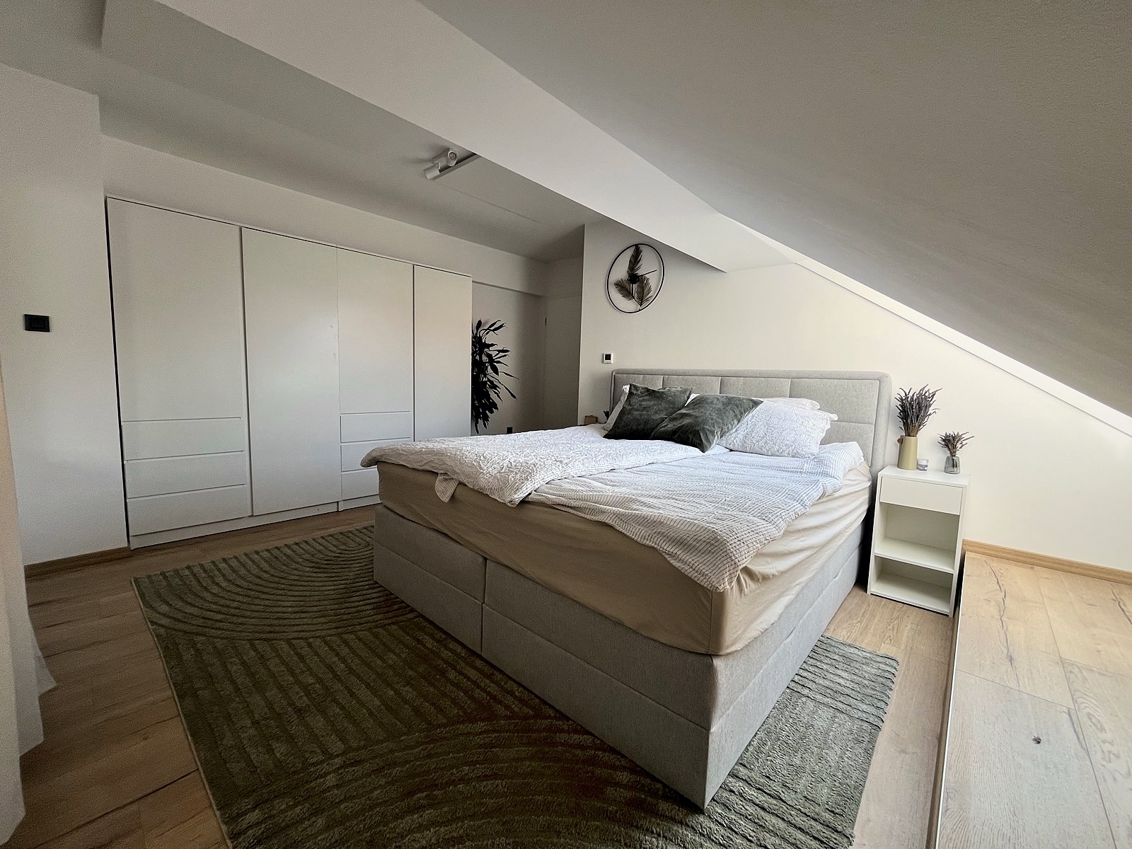 Bedside table with plant and lamp in master bedroom