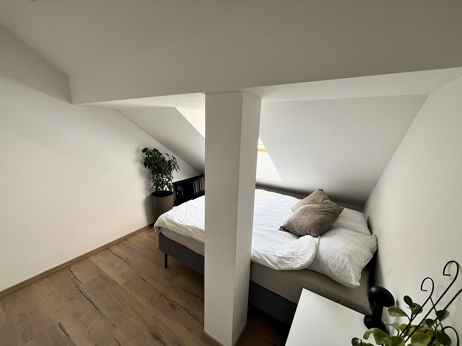 Second bedroom with queen bed visible behind a structural column