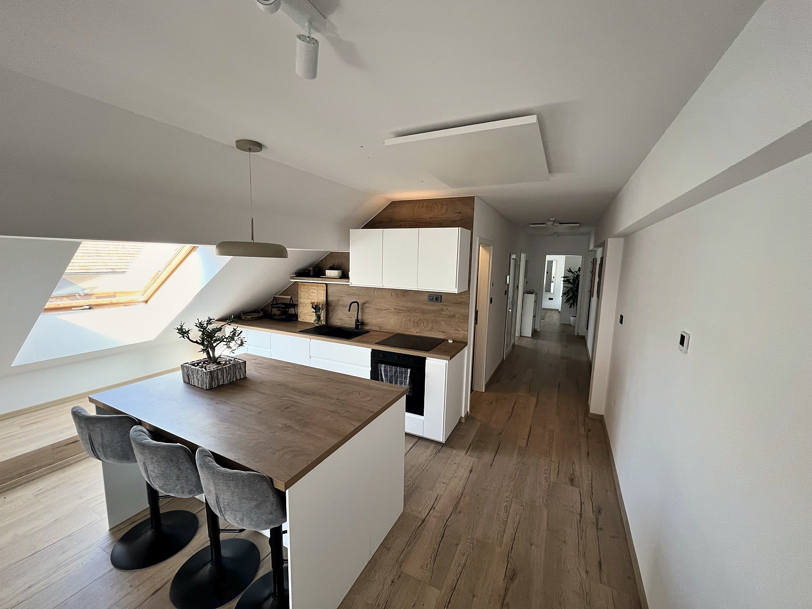 The kitchen island and breakfast bar under a skylight in the sloped attic ceiling